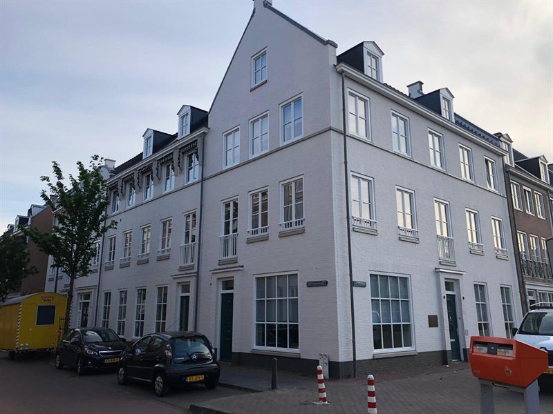 Wit afgewerkt hoekpand aan de Herselsestraat in Helmond, met de bedrijfsbus ervoor