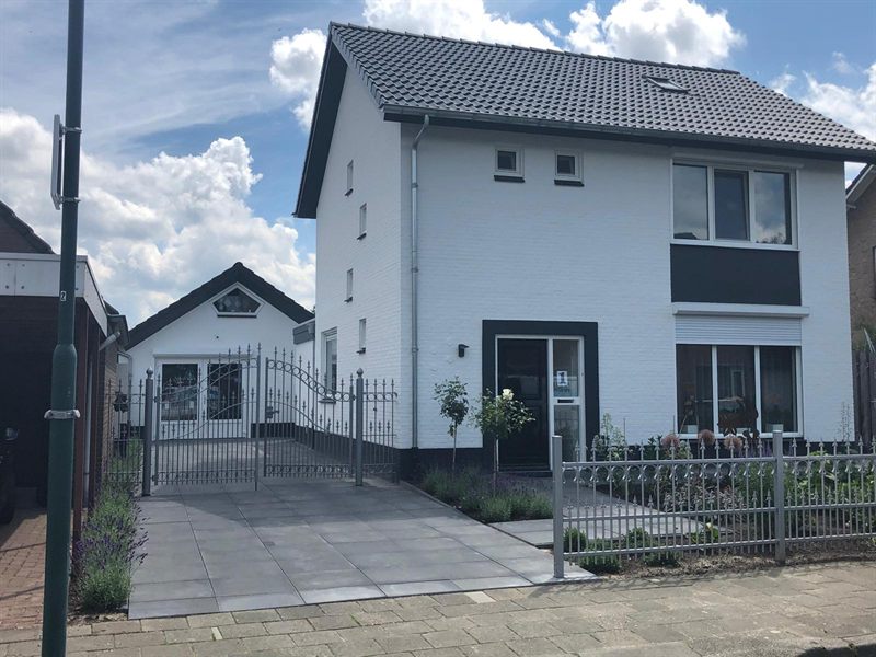 Woonhuis in Beek en Donk met wit afgewerkte gevel en antracieten kozijnen achter een smeedijzeren hek